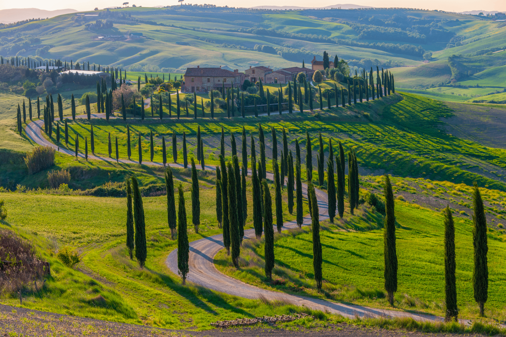 Tuscan villa with winding cypress-lined road through the rolling hills of Val d'Orcia